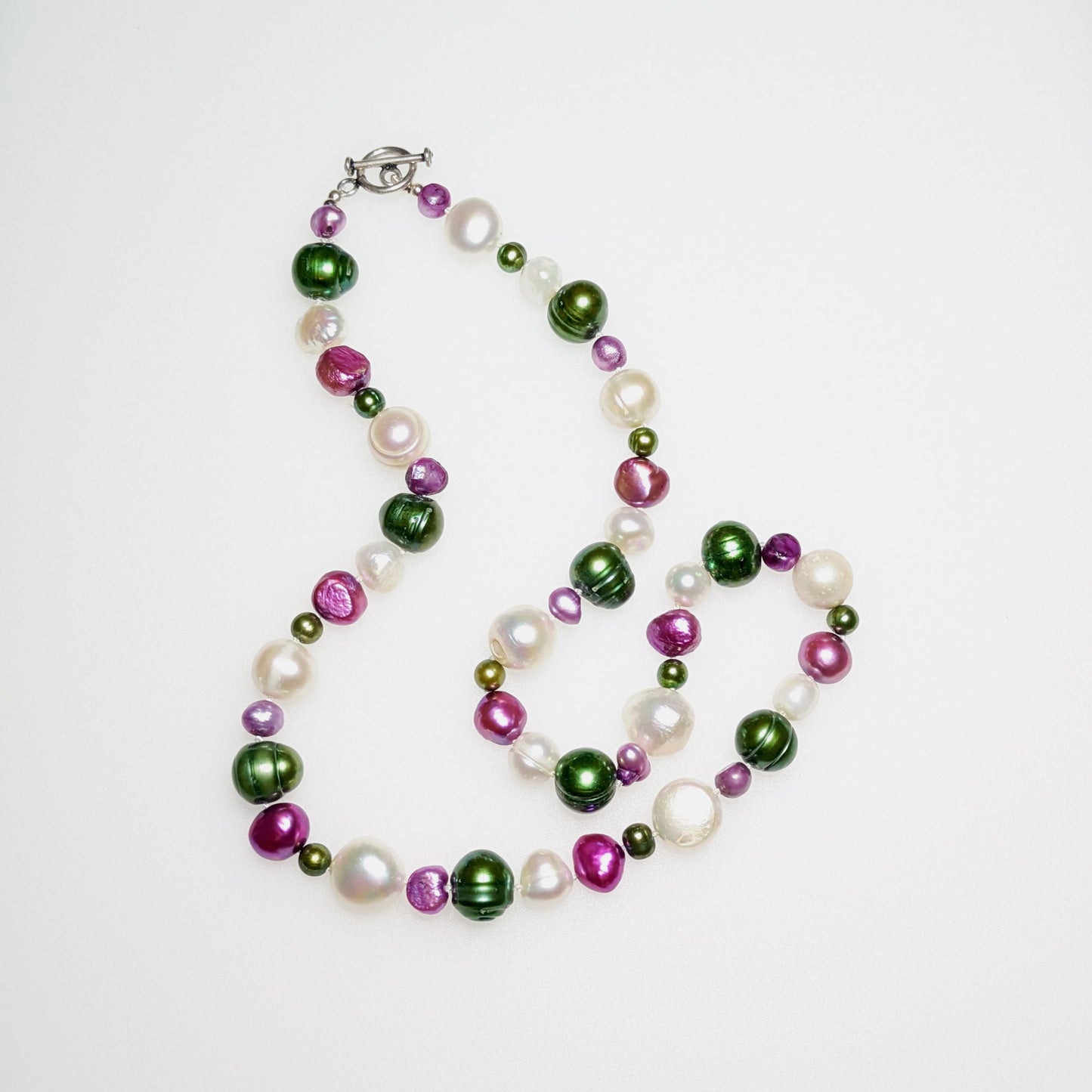 Freshwater pearl mix necklace of white, dark pink and green pearls on a silver clasp