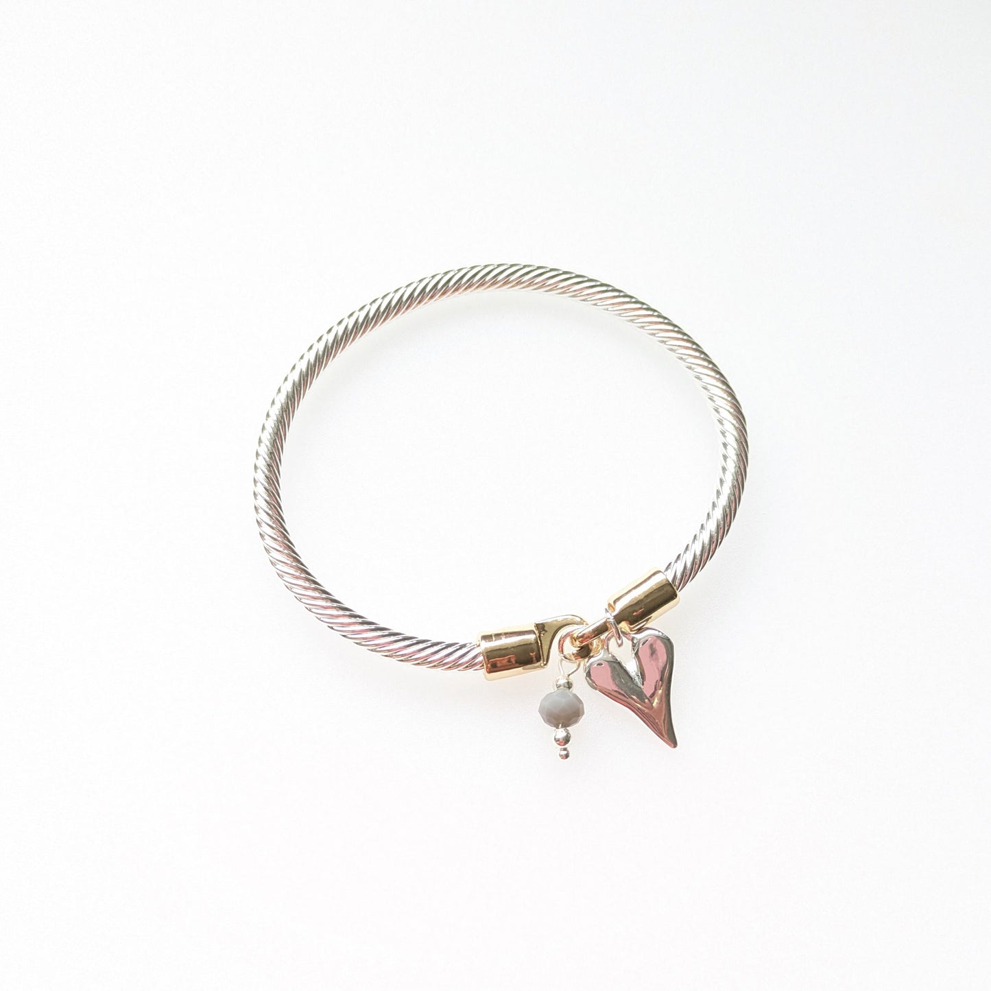 Twisted rope effect silver plated bangle with a charm on the rose gold plated clasp