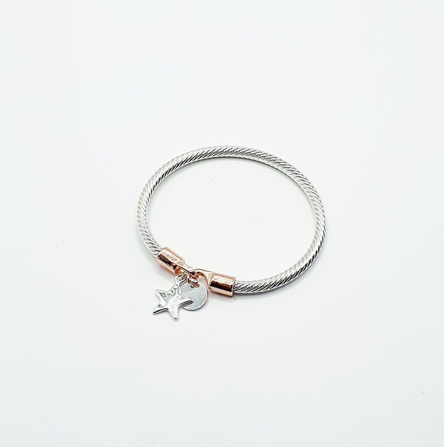 Twisted rope effect silver plated bangle with a charm on the rose gold plated clasp