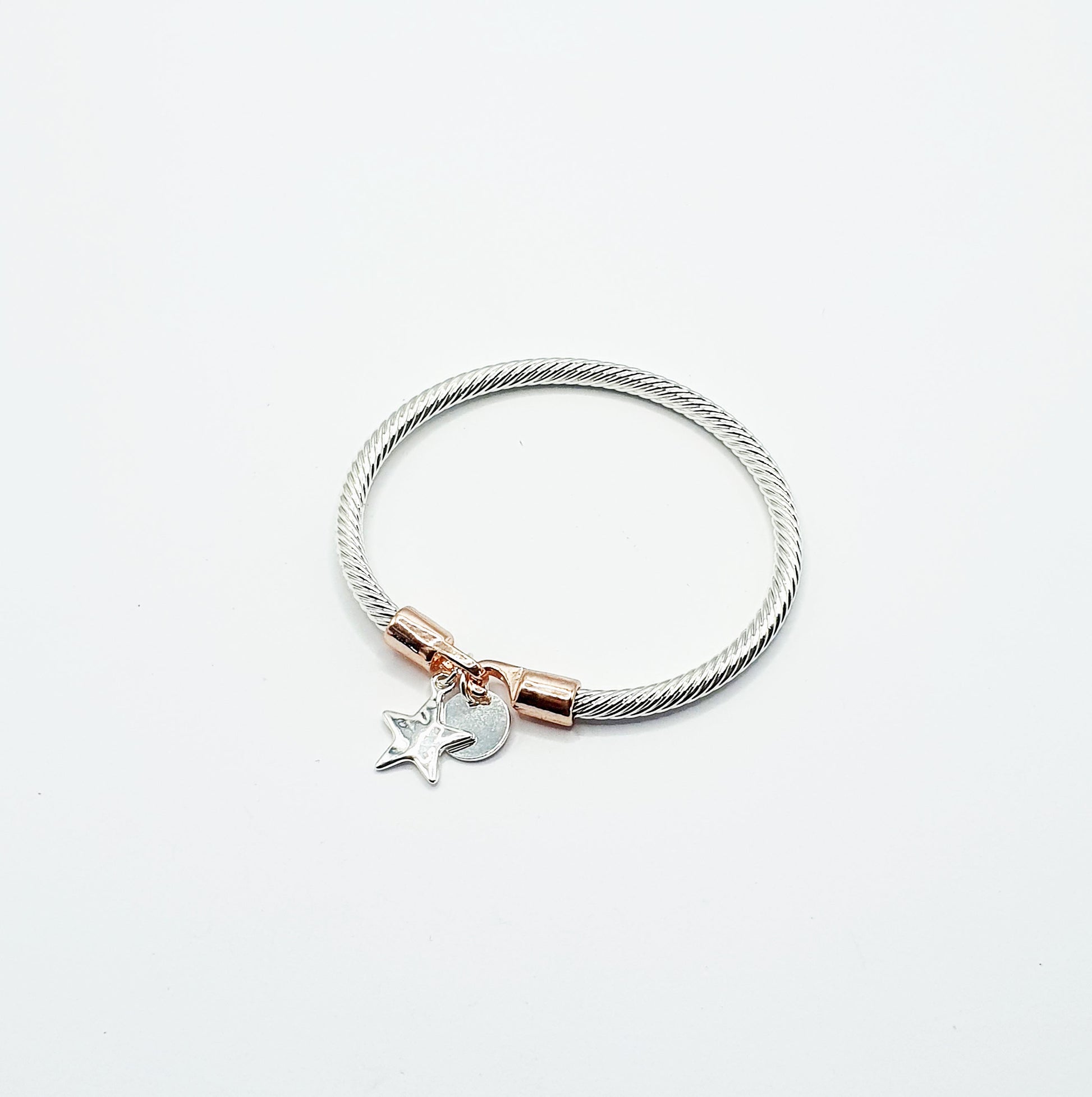 Twisted rope effect silver plated bangle with a charm on the rose gold plated clasp