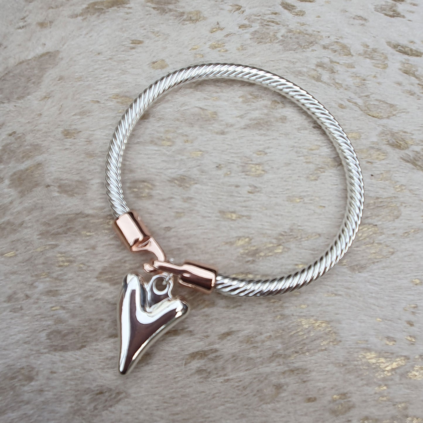 Twisted rope effect silver plated bangle with a charm on the rose gold plated clasp