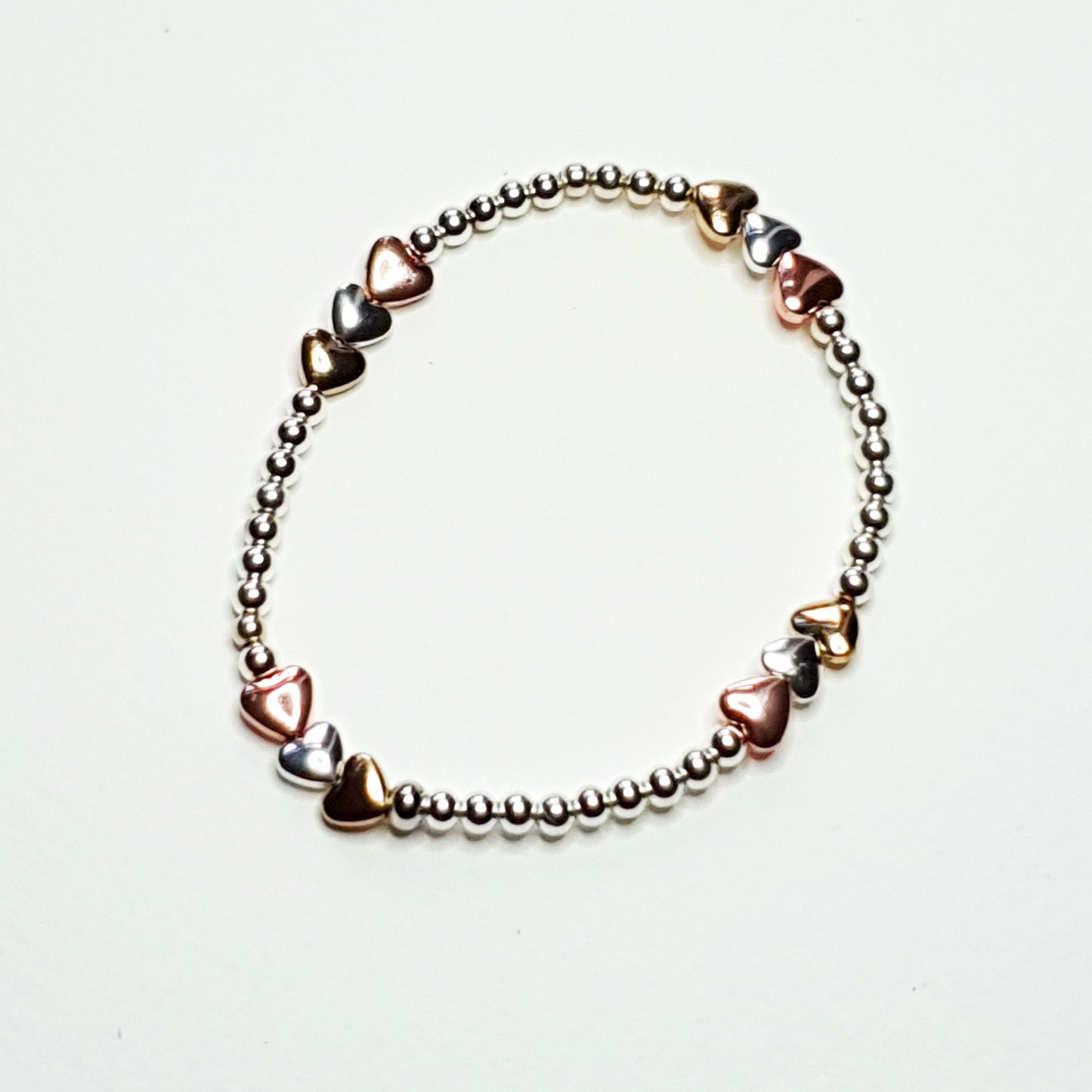 Silver and gold plated hematine hearts on an elasticated band